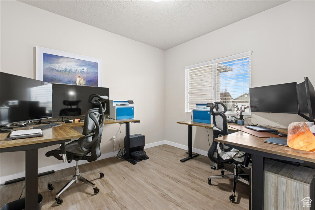 Office with a textured ceiling and light wood-type flooring