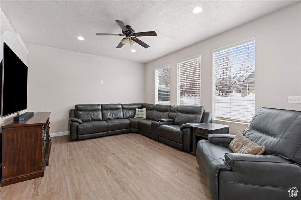 Living room featuring ceiling fan, a textured ceiling, and light wood-type flooring