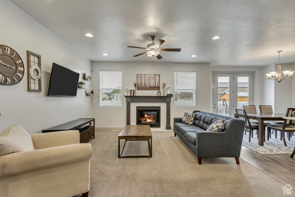 Living room featuring a healthy amount of sunlight, ceiling fan with notable chandelier, and light hardwood / wood-style flooring