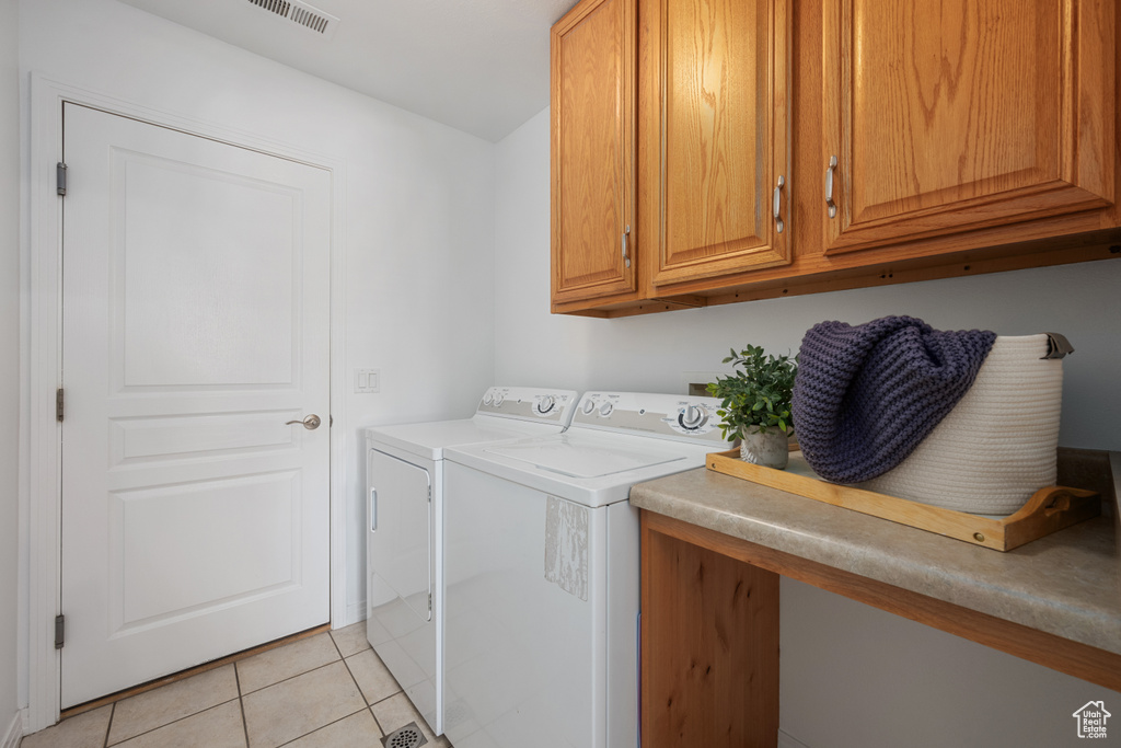 Laundry room featuring cabinets, light tile patterned floors, and independent washer and dryer