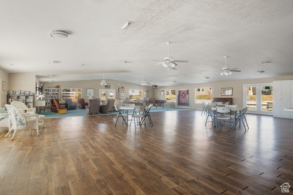Unfurnished dining area with vaulted ceiling, dark wood-type flooring, and a textured ceiling