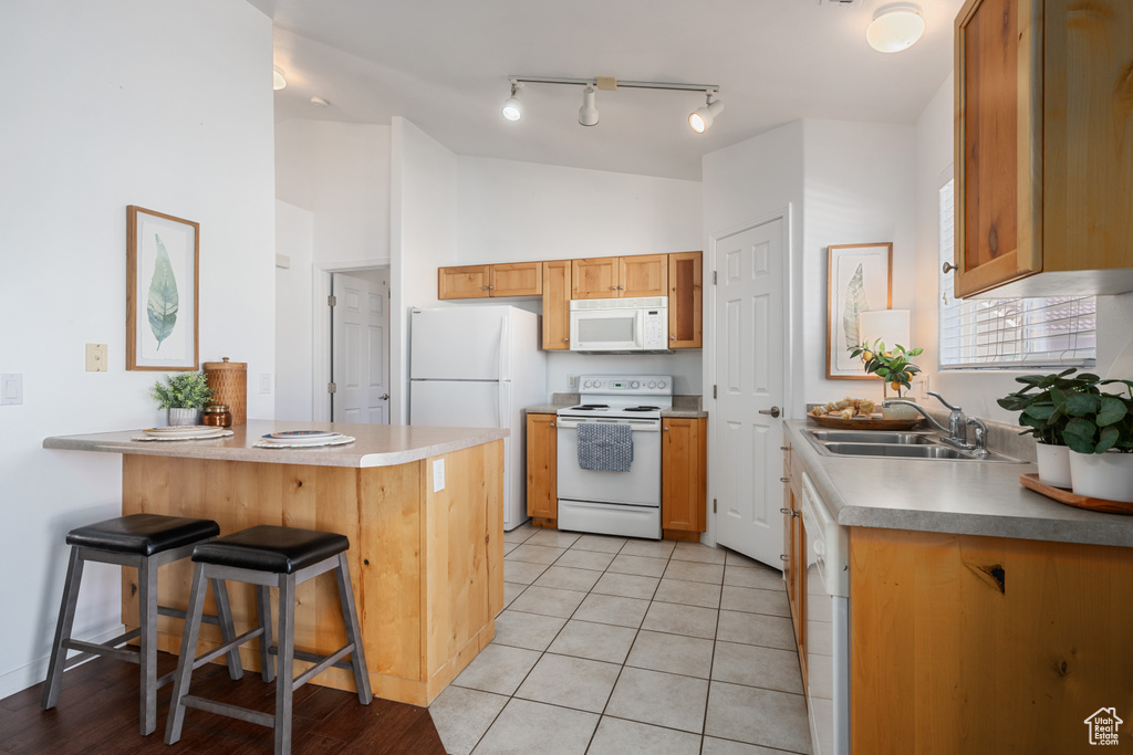 Kitchen featuring lofted ceiling, sink, a breakfast bar area, kitchen peninsula, and white appliances