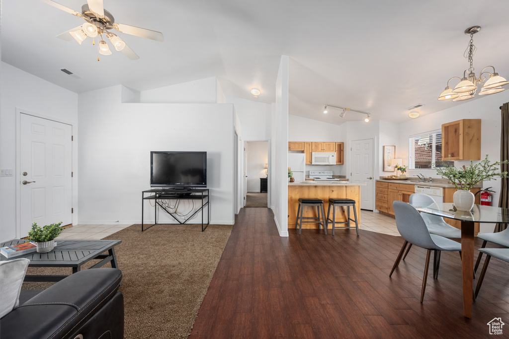 Living room with lofted ceiling, sink, ceiling fan with notable chandelier, and dark wood-type flooring