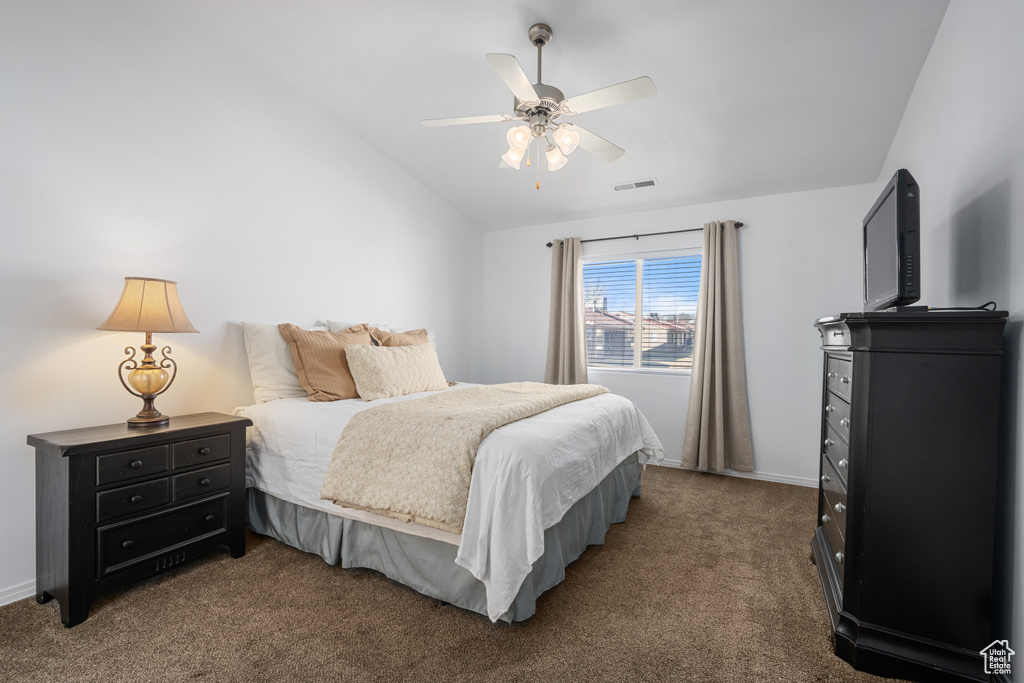 Bedroom with ceiling fan, vaulted ceiling, and dark colored carpet