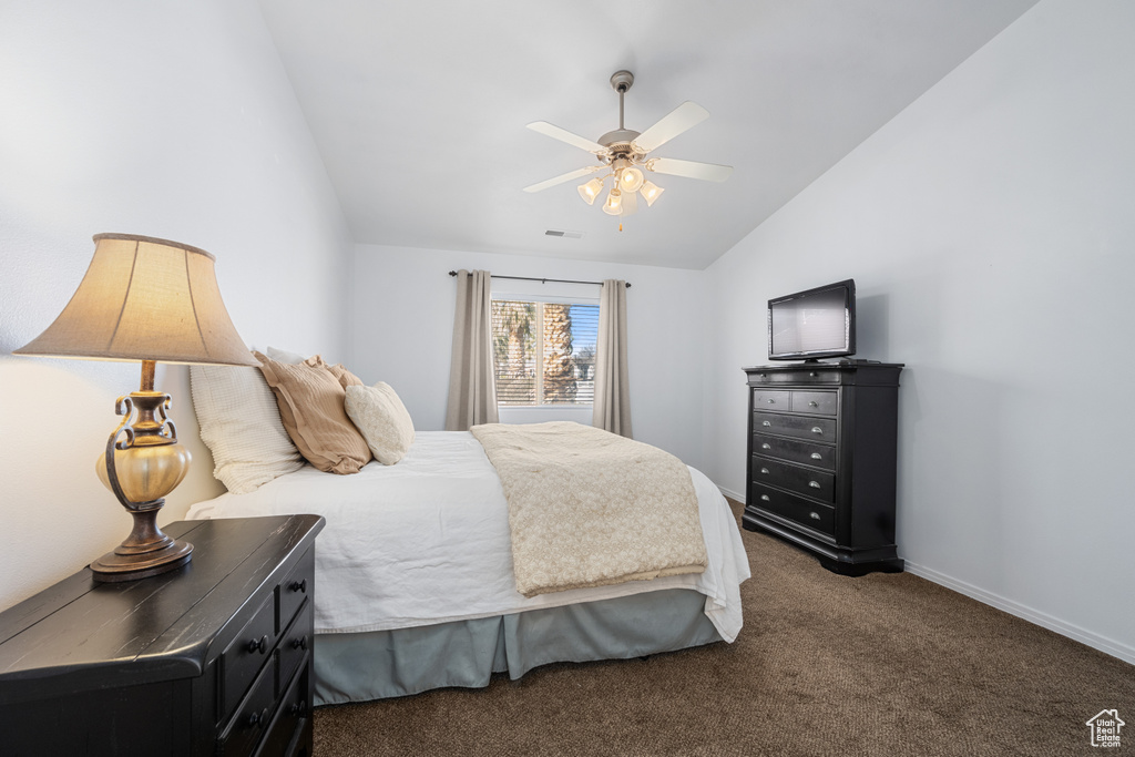 Carpeted bedroom featuring vaulted ceiling and ceiling fan