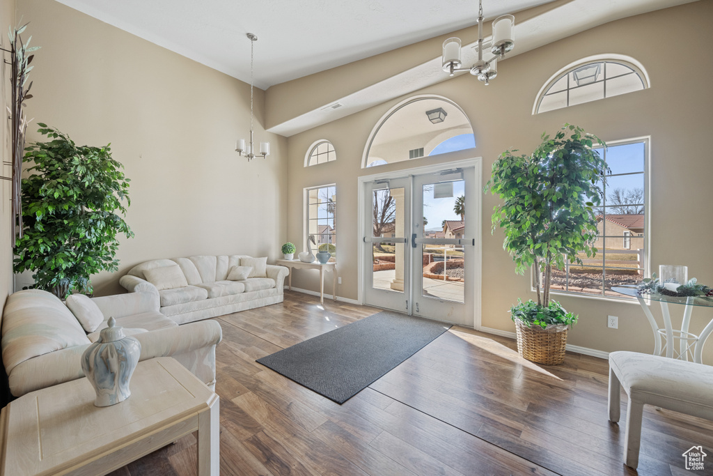 Living room featuring dark wood-type flooring, french doors, a chandelier, and a high ceiling