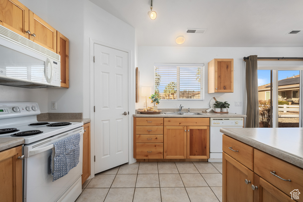 Kitchen featuring sink, white appliances, and light tile patterned flooring