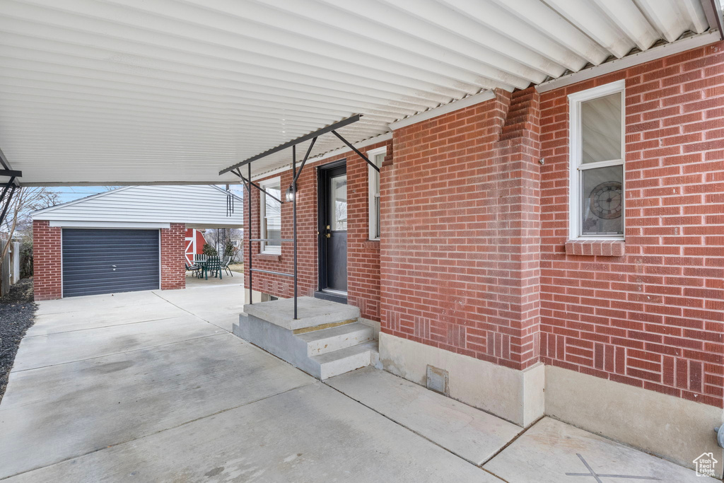 View of patio featuring a garage and an outbuilding