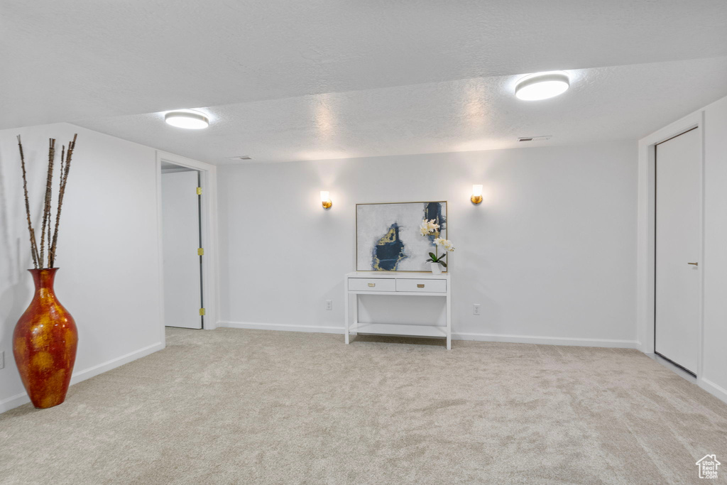 Empty room featuring light colored carpet and a textured ceiling