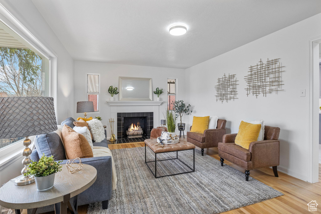 Living room with a tile fireplace and light wood-type flooring