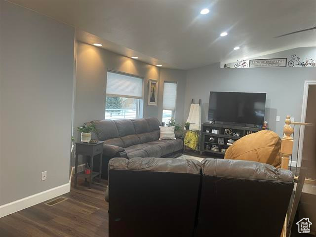 Living room with dark hardwood / wood-style flooring and vaulted ceiling
