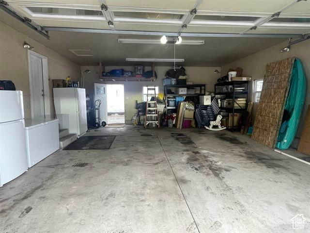 Garage featuring white refrigerator and a garage door opener