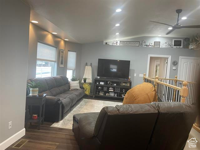 Living room with lofted ceiling, dark hardwood / wood-style floors, and ceiling fan