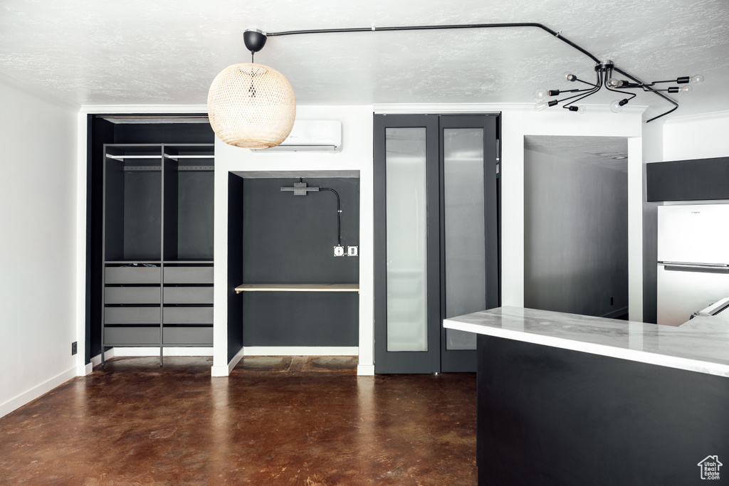 Unfurnished dining area featuring baseboards, finished concrete floors, a textured ceiling, and an AC wall unit