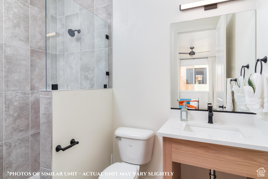 Bathroom featuring tiled shower, vanity, and toilet