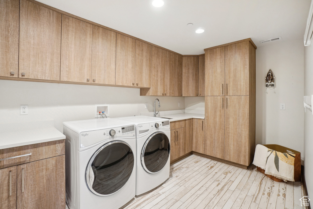 Washroom with washing machine and clothes dryer, cabinet space, light wood-style flooring, and recessed lighting