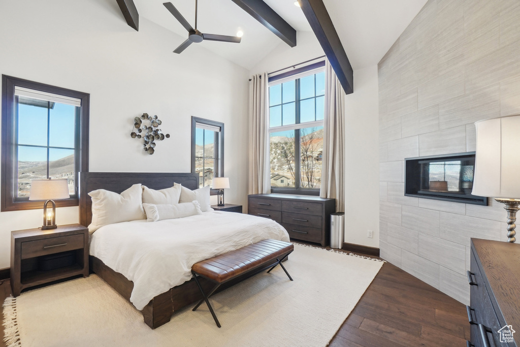 Bedroom featuring high vaulted ceiling, beamed ceiling, dark wood-style flooring, baseboards, and tile walls