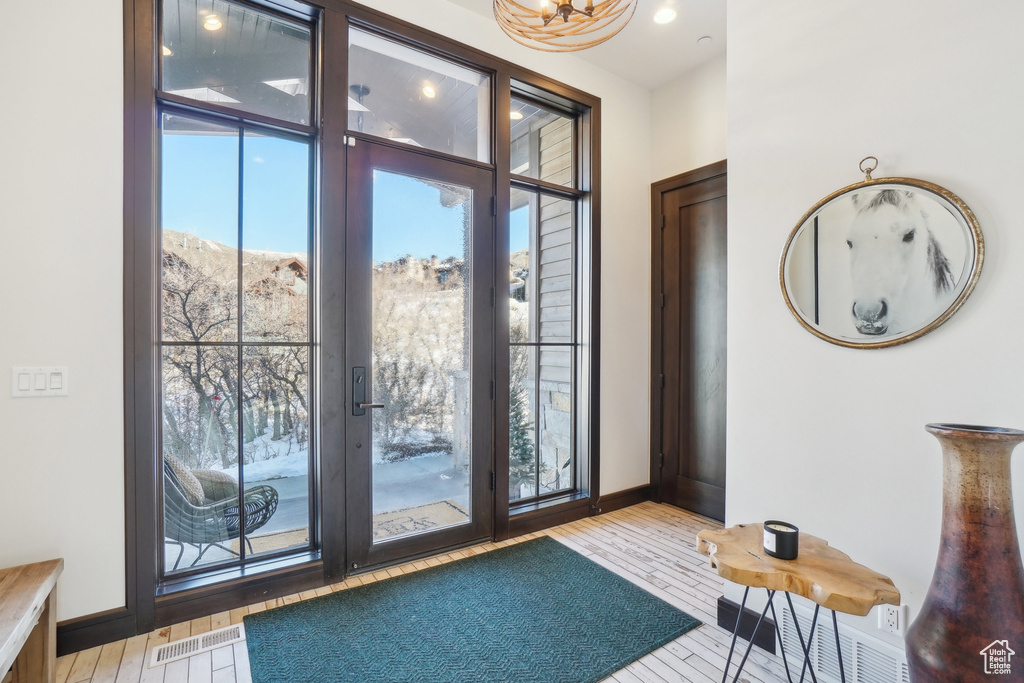 Doorway to outside featuring baseboards, hardwood / wood-style flooring, french doors, and a chandelier