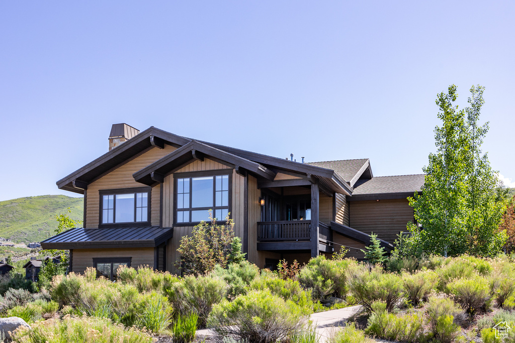 View of front of home with a chimney, a standing seam roof, roof with shingles, and a mountain view