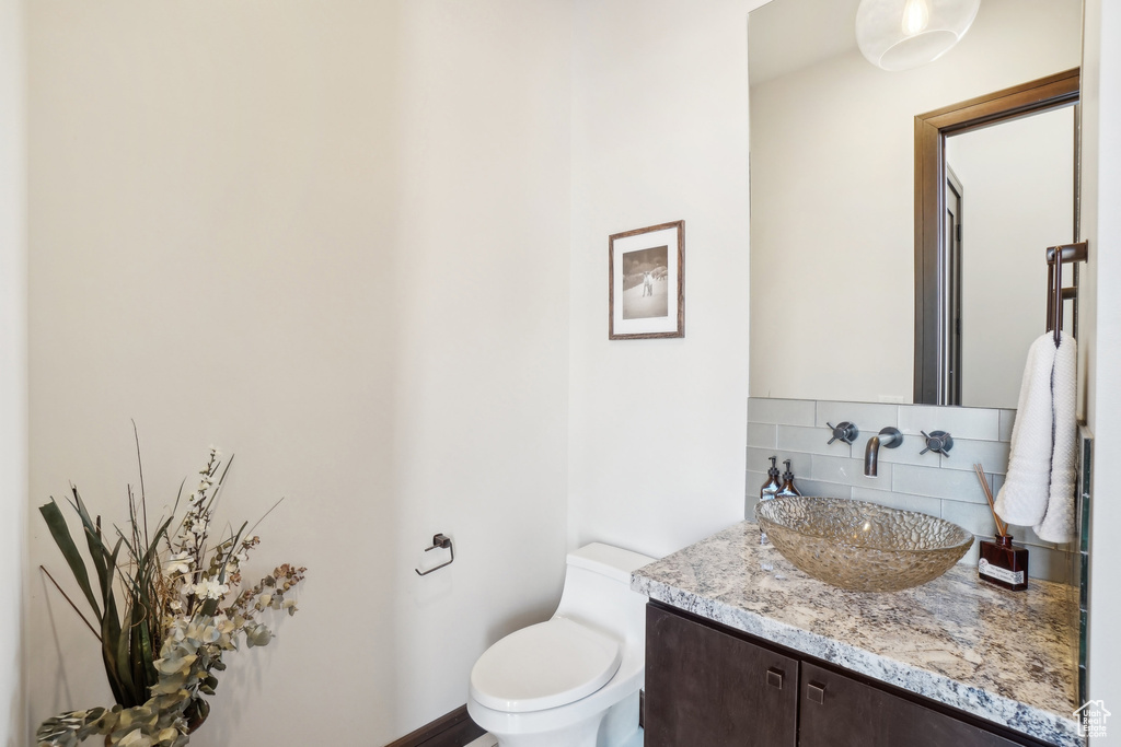 Bathroom featuring vanity, backsplash, and toilet