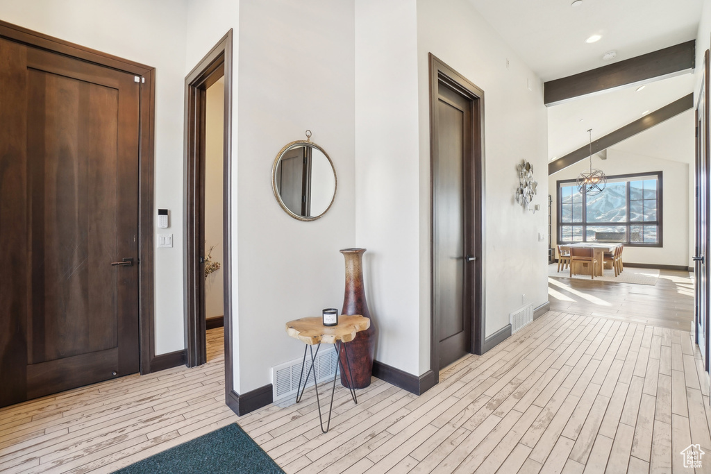 Hall featuring light wood-style flooring, baseboards, a chandelier, and recessed lighting