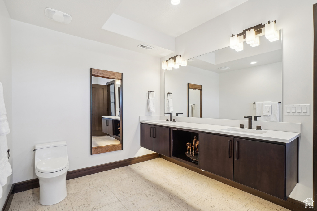 Full bathroom with double vanity, toilet, baseboards, recessed lighting, and tile patterned floors