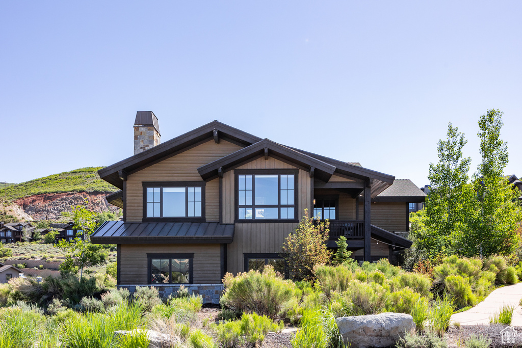 View of front of home featuring a standing seam roof, a chimney, and metal roof