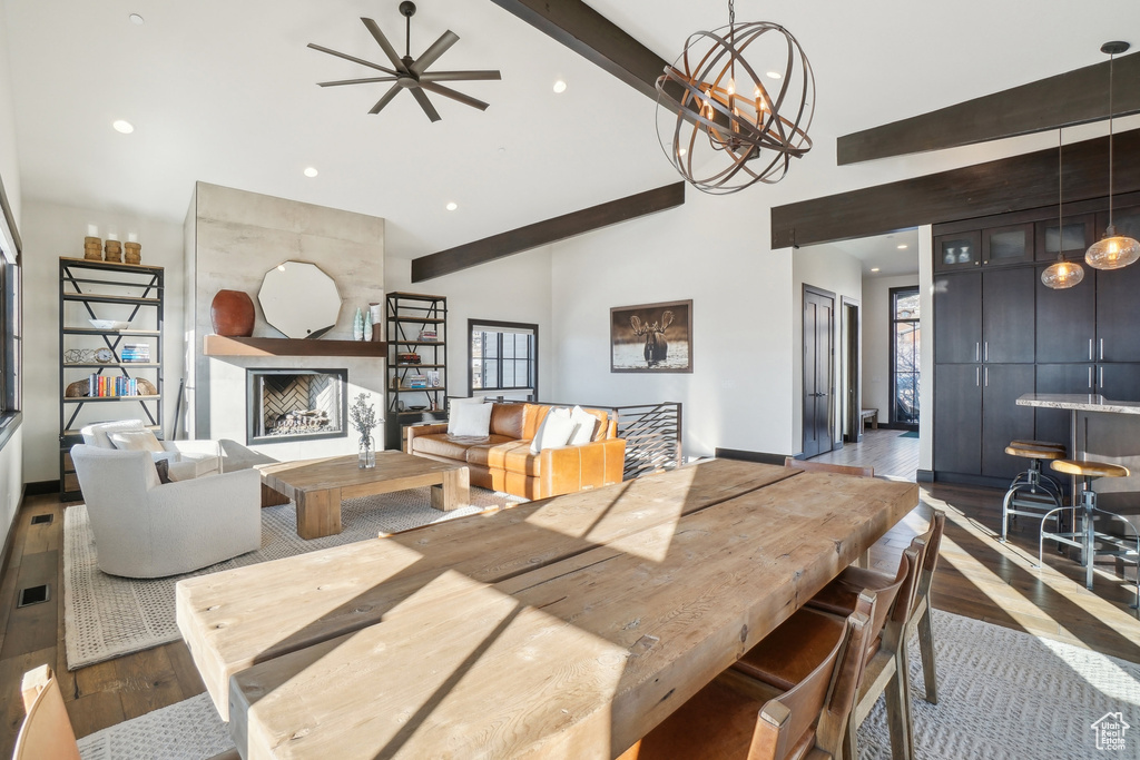 Dining area featuring high vaulted ceiling, wood-type flooring, a ceiling fan, a large fireplace, and beam ceiling