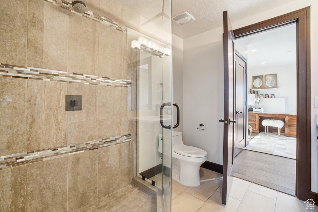 Bathroom featuring a shower stall, toilet, and tile patterned floors