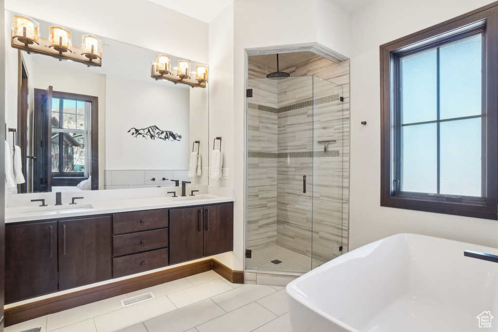 Full bathroom with a shower stall, a freestanding bath, double vanity, and tile patterned floors