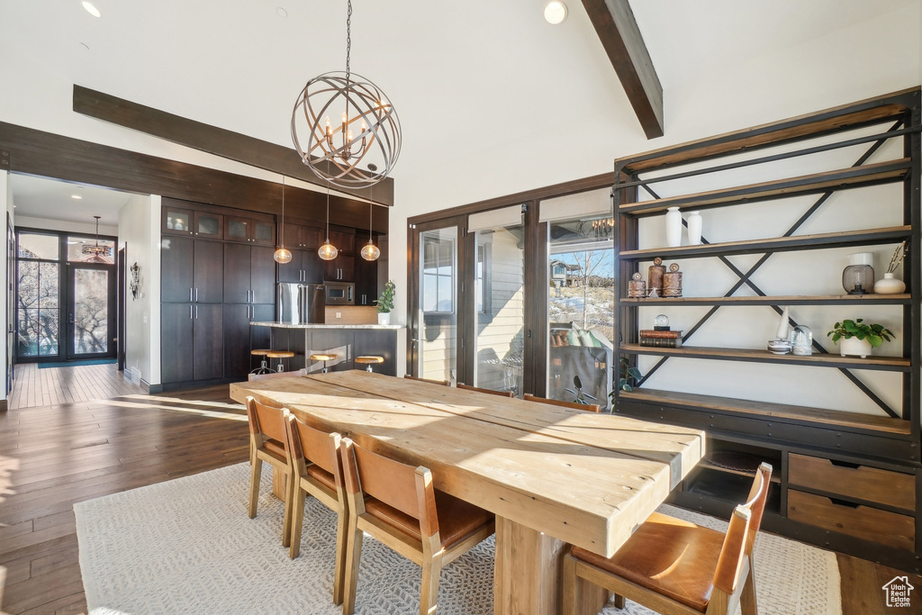 Dining area with a chandelier, a towering ceiling, dark wood-type flooring, and beam ceiling