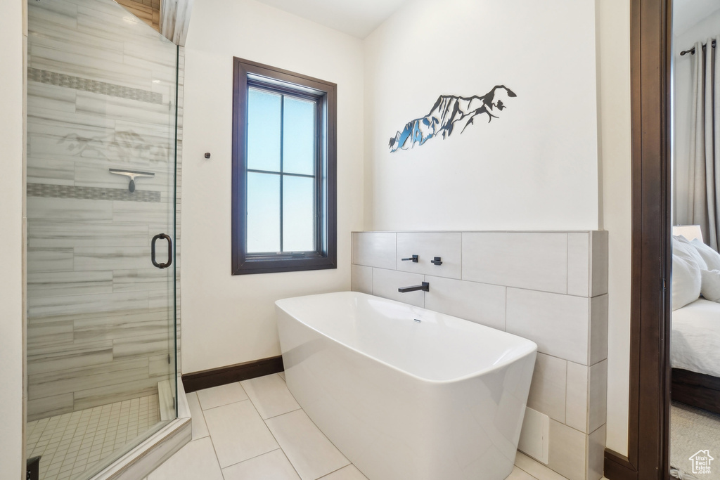 Ensuite bathroom featuring a freestanding tub, a shower stall, healthy amount of natural light, and baseboards