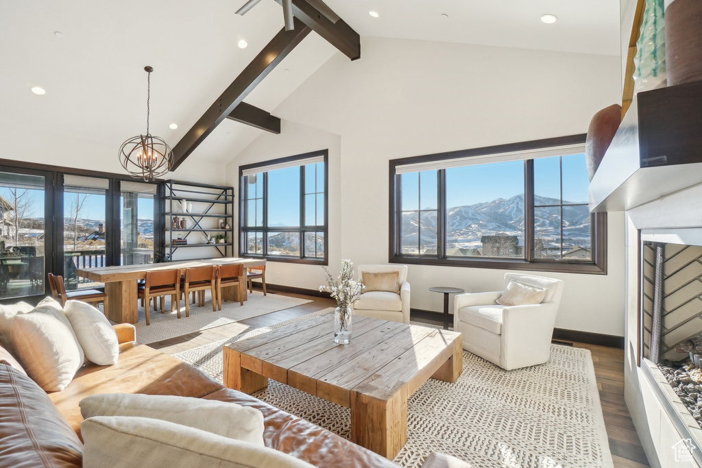 Living room featuring beamed ceiling, wood finished floors, a chandelier, plenty of natural light, and recessed lighting
