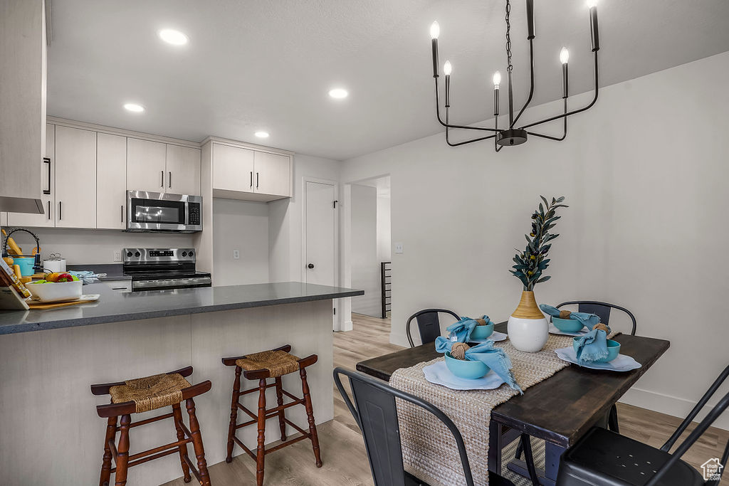 Kitchen with a breakfast bar area, light hardwood / wood-style flooring, appliances with stainless steel finishes, kitchen peninsula, and white cabinets