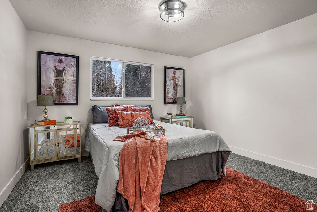 Bedroom featuring dark carpet and a textured ceiling