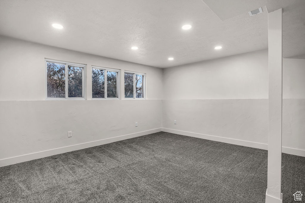 Spare room featuring dark carpet and a textured ceiling