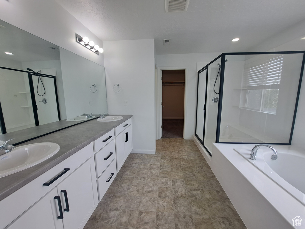 Bathroom with a stall shower, double vanity, a garden tub, a walk in closet, and baseboards