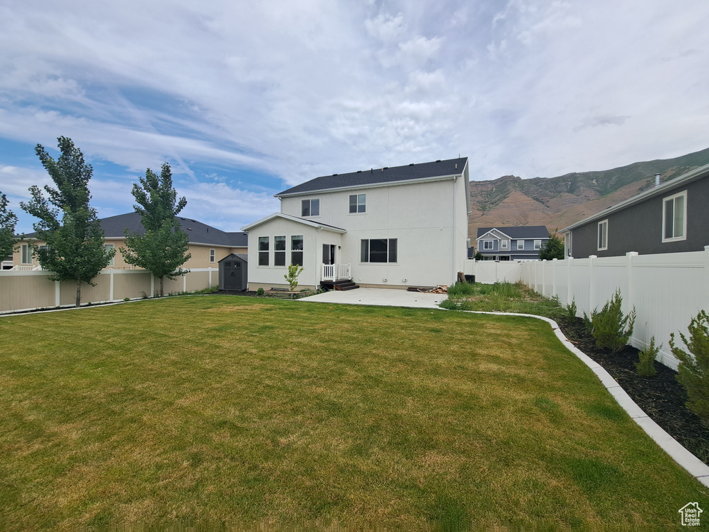 Rear view of house with a patio area, stucco siding, and a mountain view