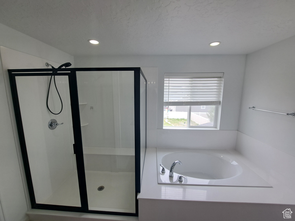 Bathroom with a stall shower, a garden tub, recessed lighting, and a textured ceiling