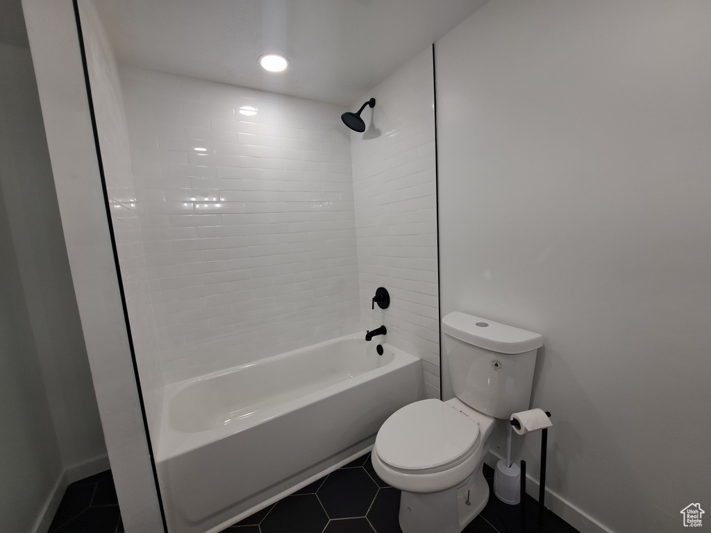 Bathroom with toilet,  shower combination, tile patterned flooring, and baseboards