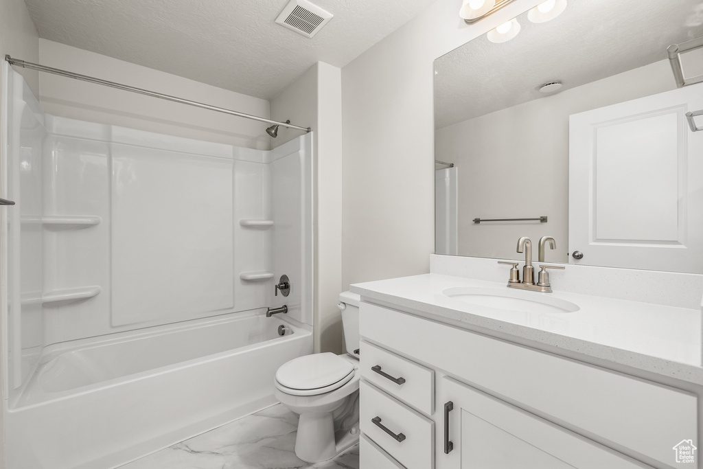 Full bathroom featuring vanity, toilet, shower / bathtub combination, and a textured ceiling