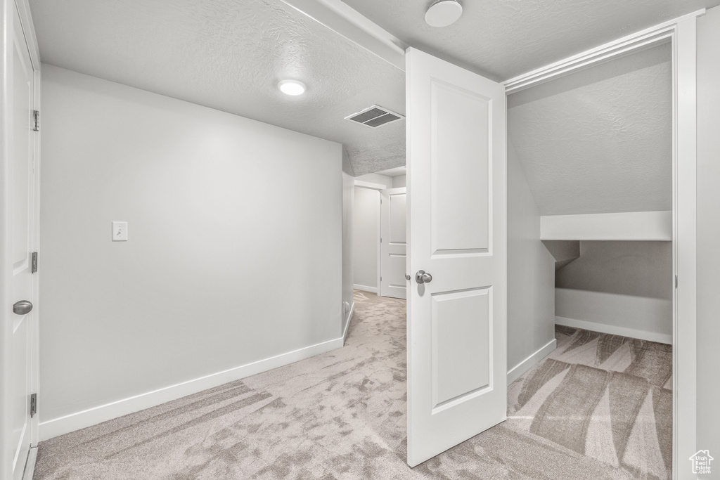 Interior space with light colored carpet and a textured ceiling