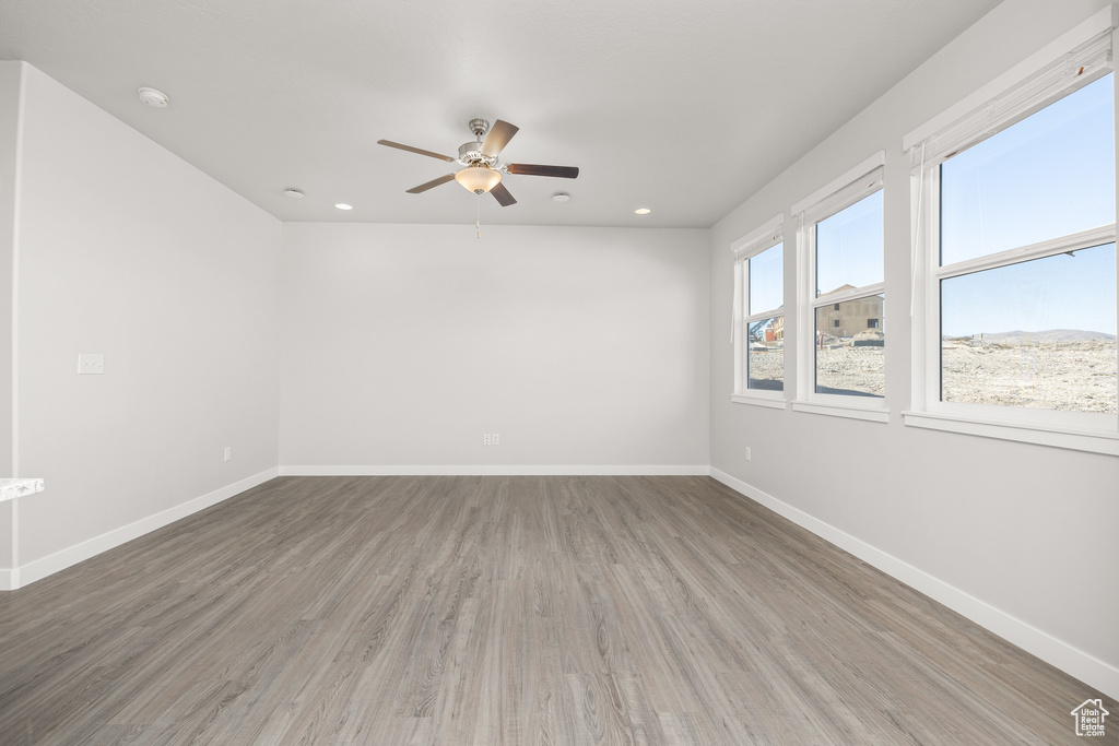 Empty room with hardwood / wood-style floors and ceiling fan