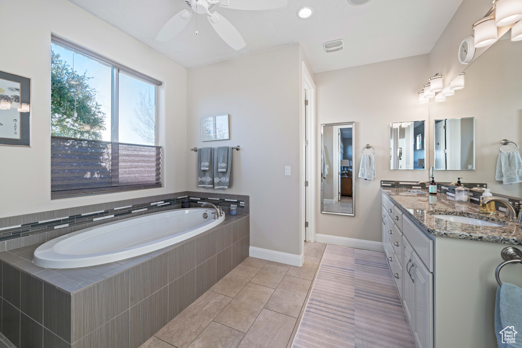 Bathroom featuring tile patterned flooring, vanity, and a relaxing tiled tub