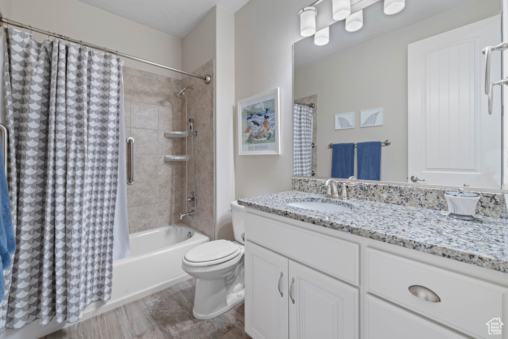 Full bathroom featuring shower / bath combination with curtain, vanity, and toilet