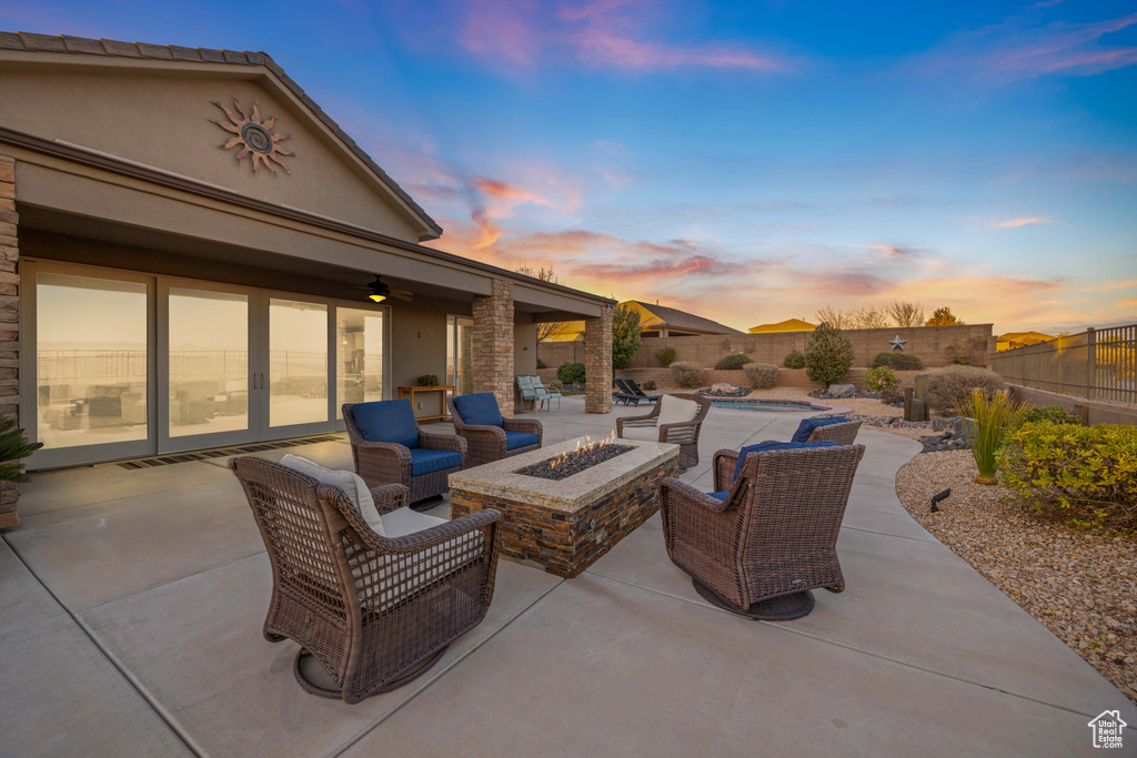 Patio terrace at dusk featuring ceiling fan and a fire pit