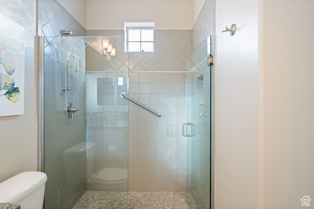 Bathroom featuring toilet and a shower with shower door