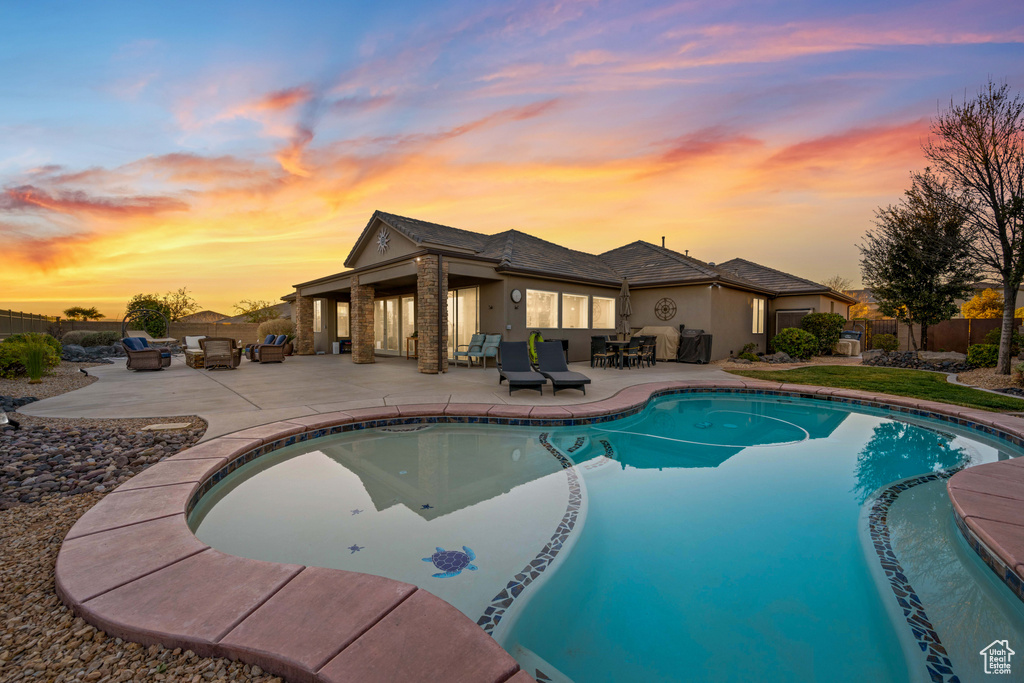 Pool at dusk featuring a patio area