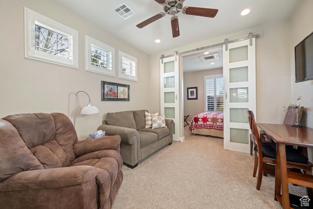 Living room with a barn door, light carpet, and ceiling fan