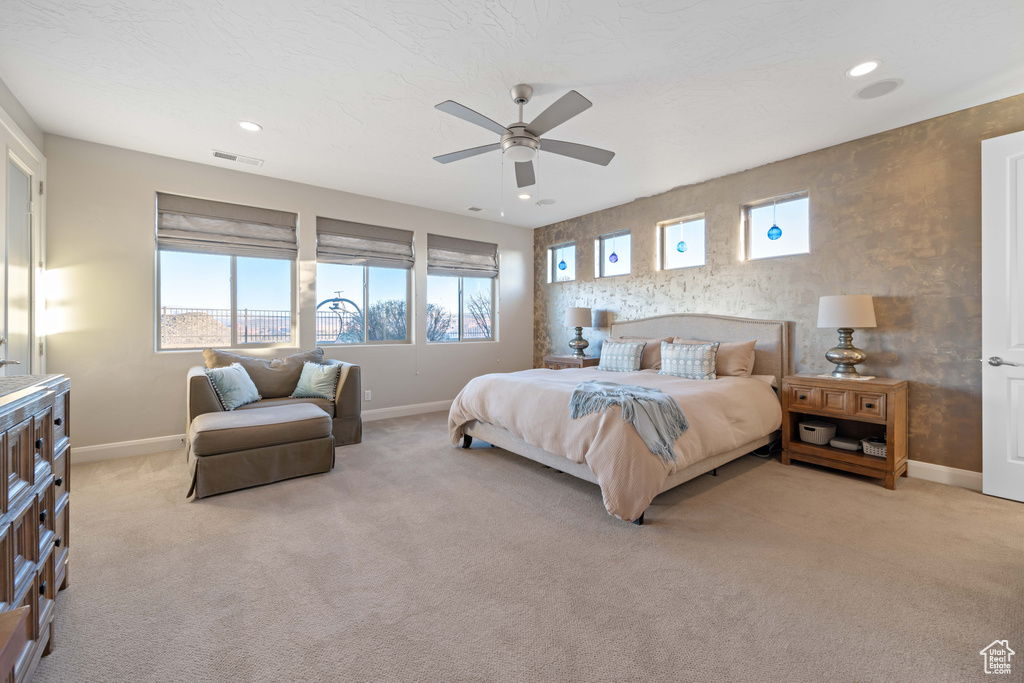Carpeted bedroom featuring ceiling fan and multiple windows